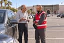 Meknès : un automobiliste âgé discute avec un dépanneur, la porte Bab Mansour en arrière-plan.