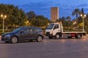 Rabat : une voiture et une dépanneuse stationnées près des jardins, la tour Hassan à l’arrière-plan.
