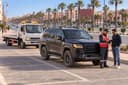 Laâyoune : un dépanneur et un automobiliste discutent près d’un SUV noir, sur un boulevard bordé de palmiers.