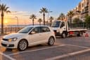 Mohammédia : une citadine et une dépanneuse sur un parking côtier au coucher du soleil, triangle posé.